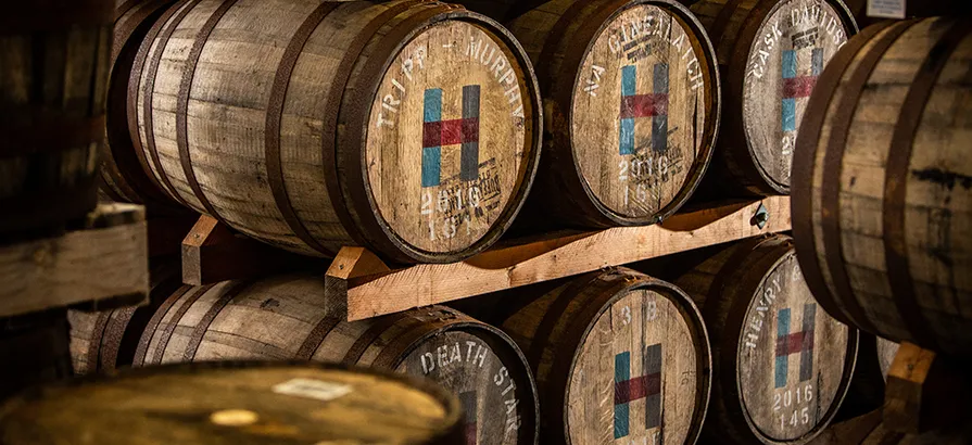 Casks with Isle of Harris logo and maturation date painted on the lid stacked on shelves in the warehouse