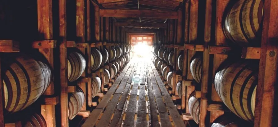 Sunlights at the end of the hallway with two shelves full of casks lying on two sides in Maker's Mark warehouse