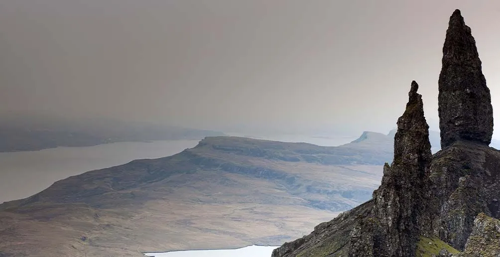 The famous rock Old Man of Storr standing on the right of the picture overlooking slopes and the Sound of Raasay covered in fog