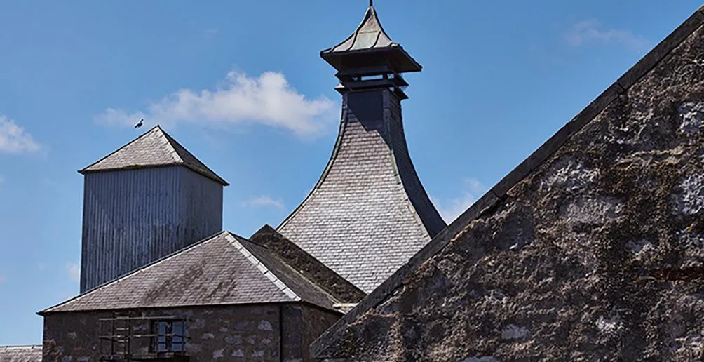 Brora distillery building with walls made of stones and an extraordinary pagoda-style roof on a sunny day