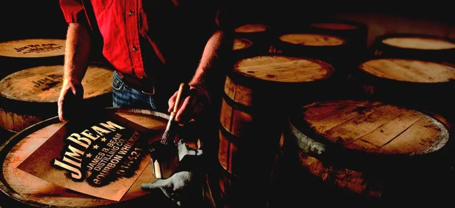 Employee painting Jim Beam's name and batch nummber on a barrel's lid