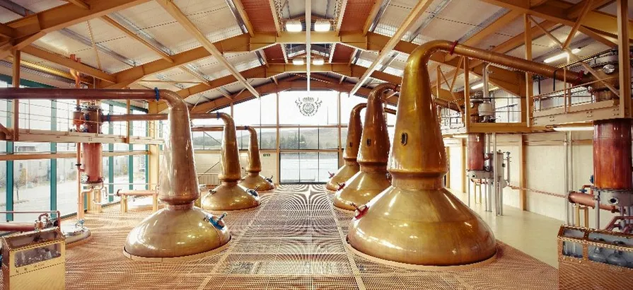 Sechs kupferne Pot Stills im Inneren des Destillierhauses von Glenlivet mit Blick auf die Bucht durch das Fenster