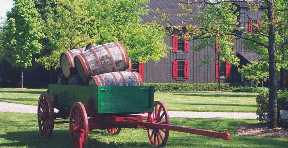 Green cards holding five barrels on top of each other in front of the wooden building with red windows