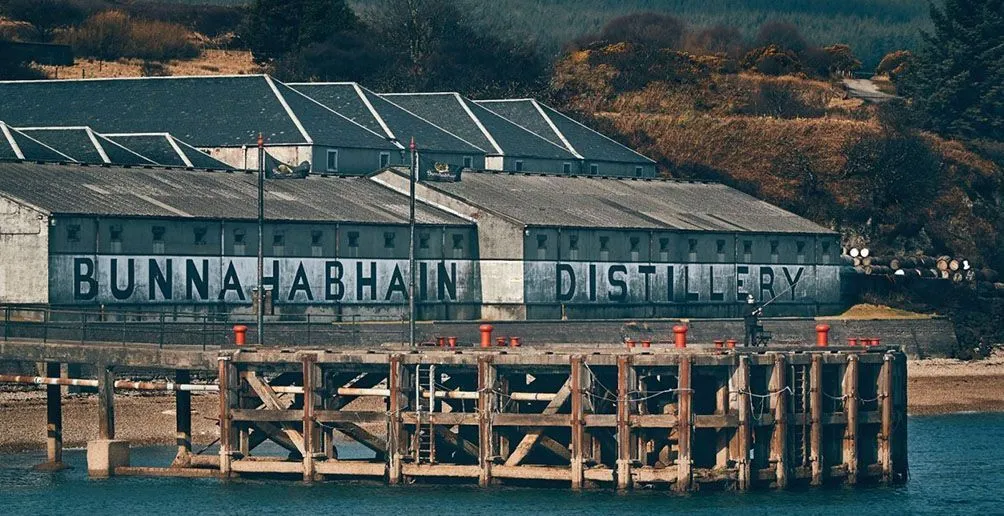 Bunnahabhain distillery building with its name painted on the front wall viewed from the harbour