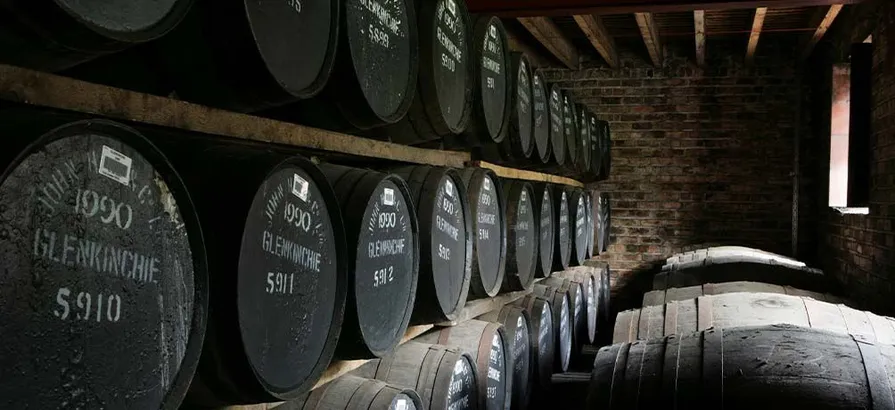 Casks with numbered lids stacked in shelves and lying in a row on the floor in Glenkinchi's warehouse