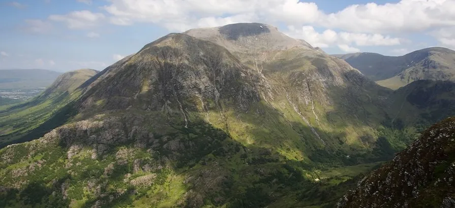 Overlooking the huge green mountain Ben Nevis with some clouds on a blue sky in the background