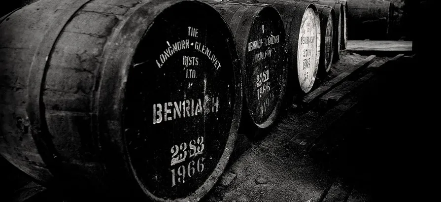Black and white photo of casks in Benriach distillery with its name and year painted on them