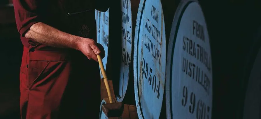 An employee tighting up the lid of a cask at Strathisla distillery