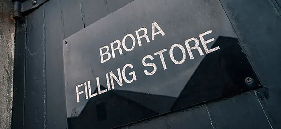 Black and white picture of a close view on the sign of Brora Filling Store on the door