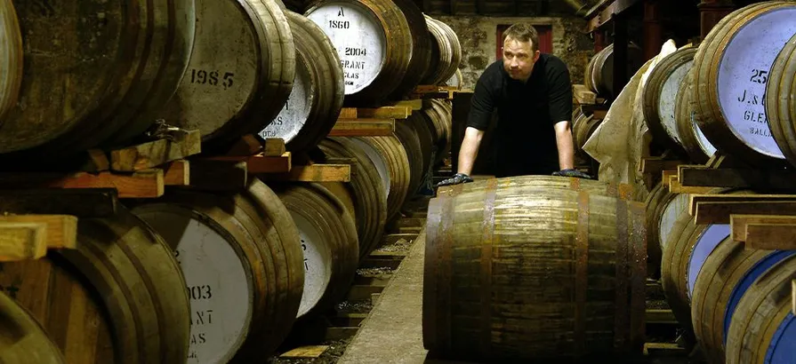 Employee at Glenfarclas's warehouse rolling a cask along two cask shelves