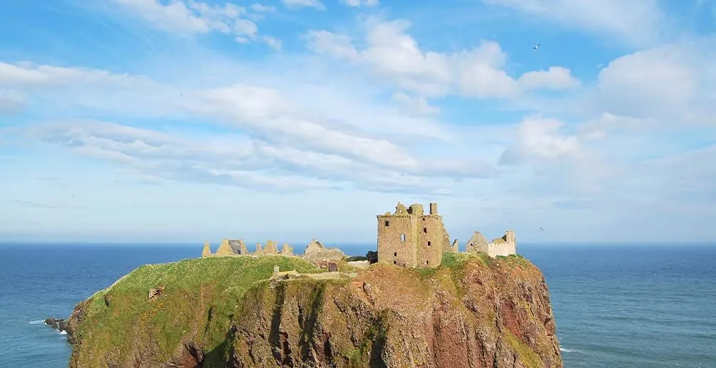 Footage of a castle located on a mountain with sky and oncean in the background