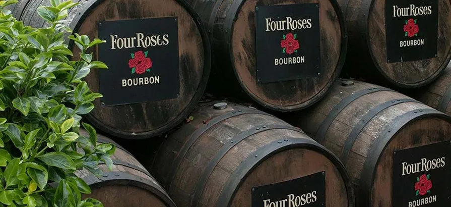 Casks stacked on top of each other with Four Roses logo on the lid hidding behind a bush