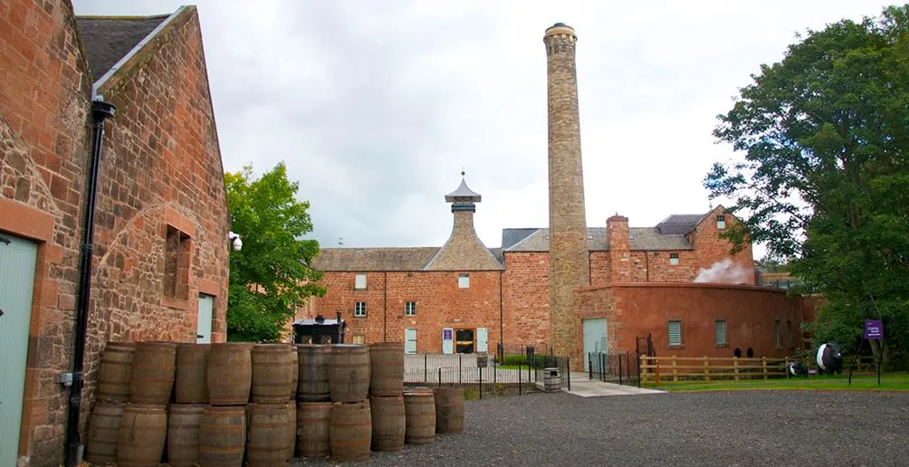 Barrels stacked in front of Annandale distillery buildings with teracotta coloured bricks