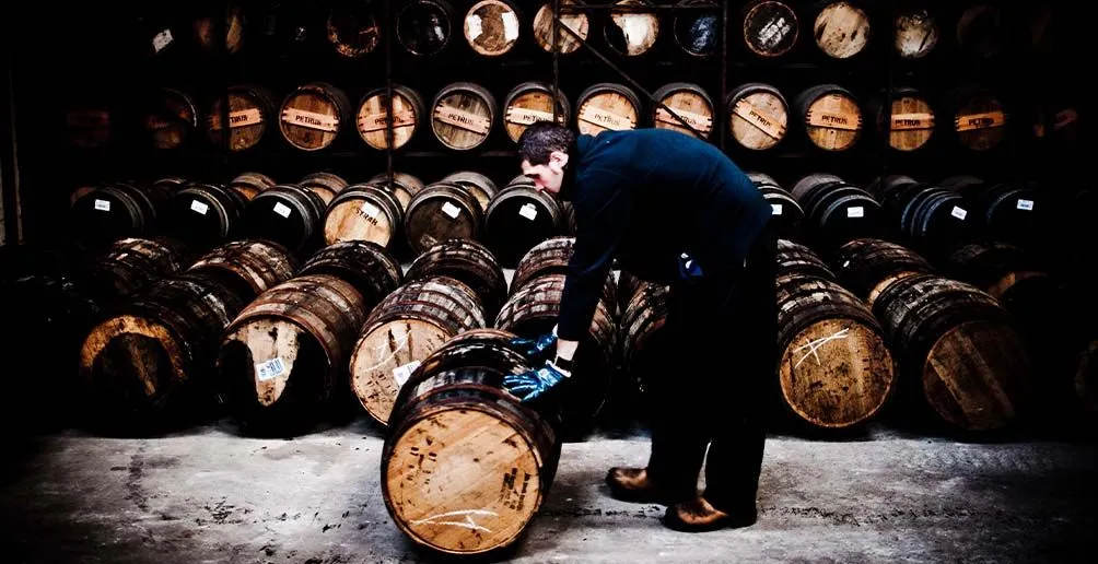 Employee at Bruichladdich distillery moving a cask in front of a cask shelve in the warehouse