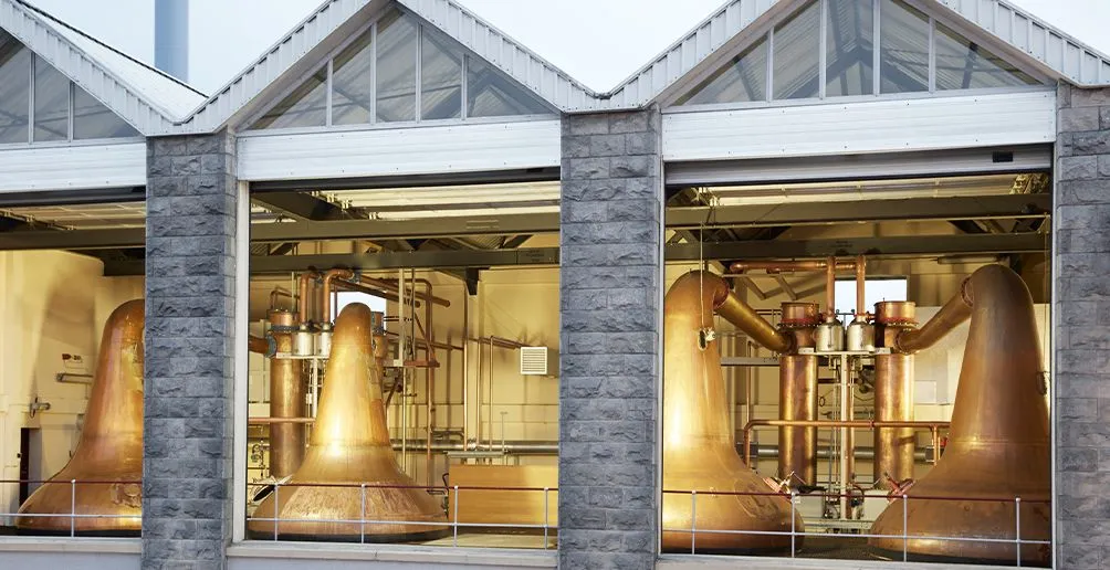 Brennhaus der Destillerie mit vier kupfernen Pot Stills und dem Mauerwerk des Brennhauses