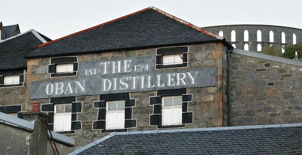 Exterior view of Oban distillery's stone building with its name and year of establishment painted on the wall