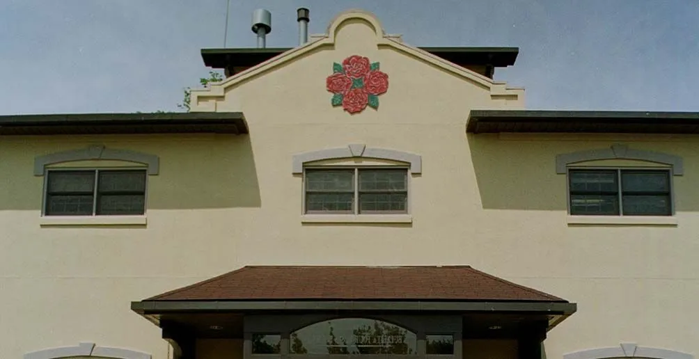 The front of Four Roses' distillery building with its logo attached on the wall