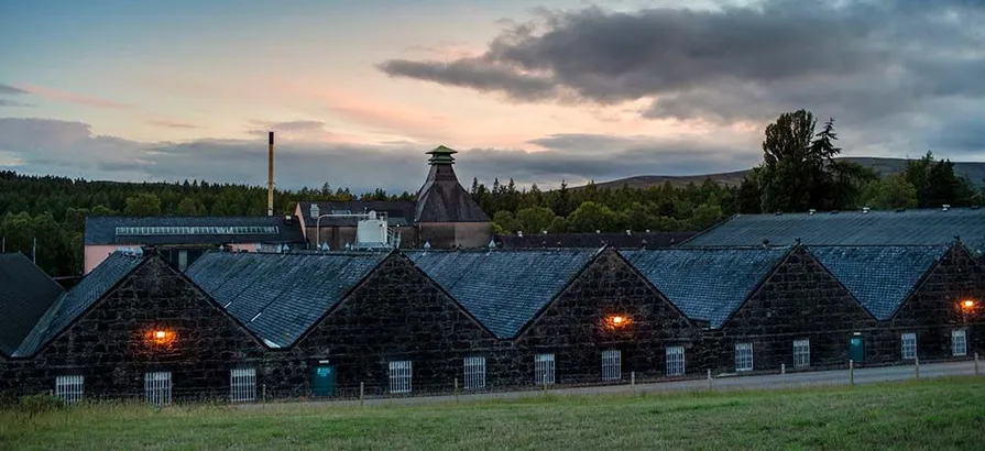 Knockando's stone warehouses with the lights turned on during sunset