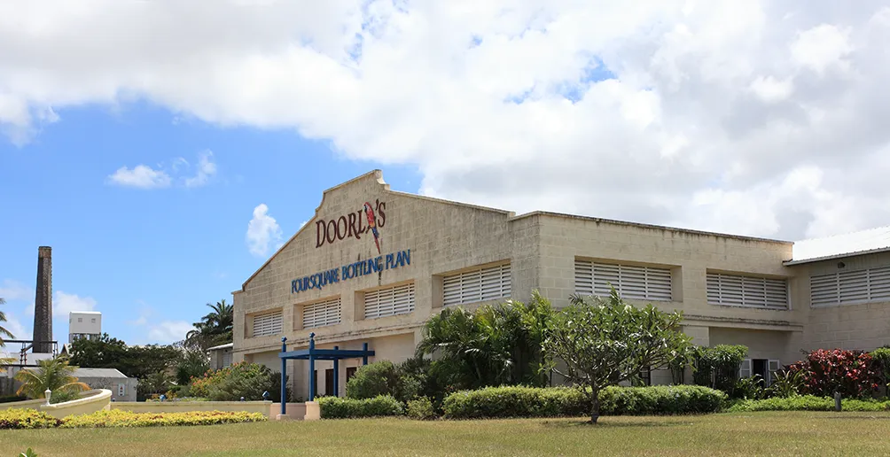 Doorly's bottling plan building with its logo on the wall surrounded by green nature