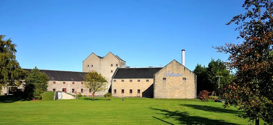 Ballantine's building located on a green yard  and surrounded by trees on a nice day