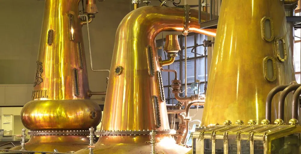 Three shiny copper pot stills in one of Suntory's distilleries