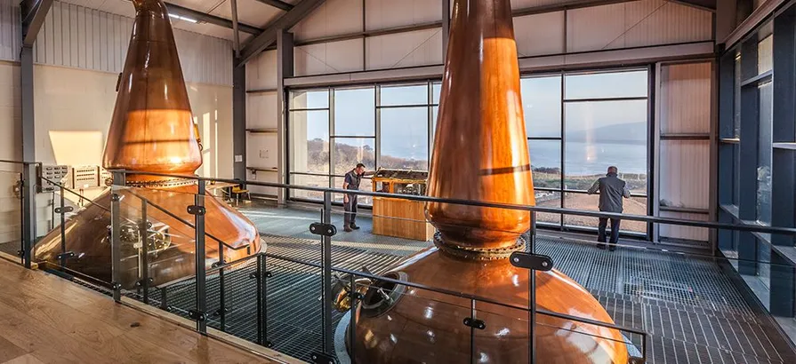 Interior view of the distillery's still house with two copper pot stills with view on the bay