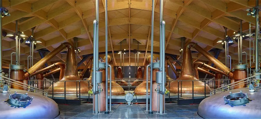 Modernes Interieur der Brennerei von Macallan mit verschiedenen kupfernen Brennblasen und einer Holzdecke