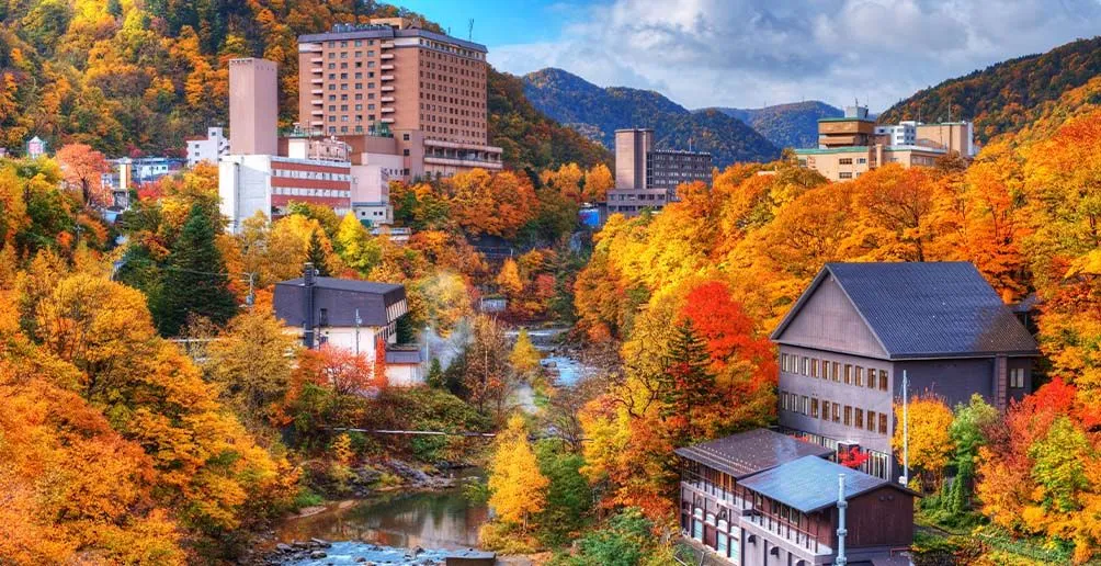 A town in Japan with a stream running through surrounded by yellow trees in autumn