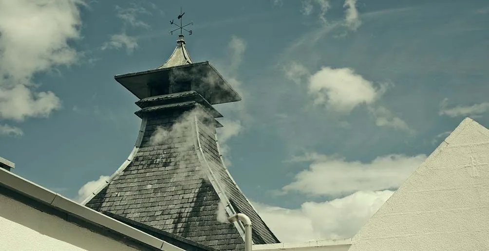 Steam coiling from Craigellachie's pagoda-style roof with blue sky in the background