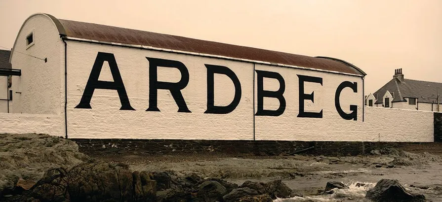 Eine Seitenansicht eines Gebäudes in der Ardberg-Brennerei mit seinem Namen an der Wand