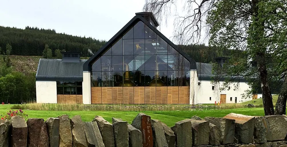 Dalmunach's still house made of glass with metal dark roof located in harmony with nature