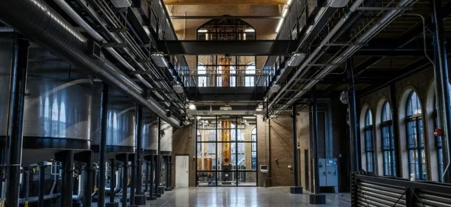 Hallway inside of Angel's Envy distillery with a row of washbacks on the left leading to a still room