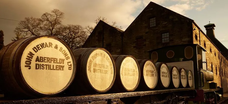 Aberfeldy' casks with its name painted on the lids stacked on the train next to the distillery building