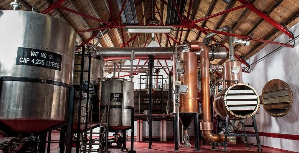 Vats and a chamber inside of Balmenach distillery with a washback in the background