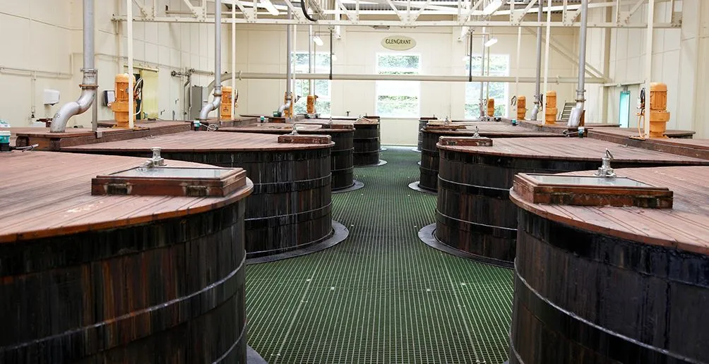 Interior of Glen Grant distillery with nine wooden mash tuns standing in two rows