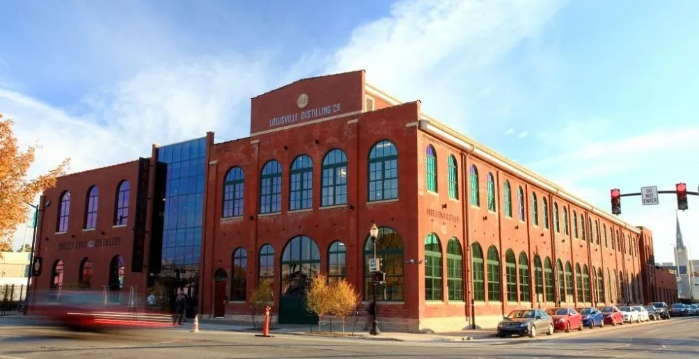 Red brick building of Angel's Envy with its name painted on the wall standing against blue sky