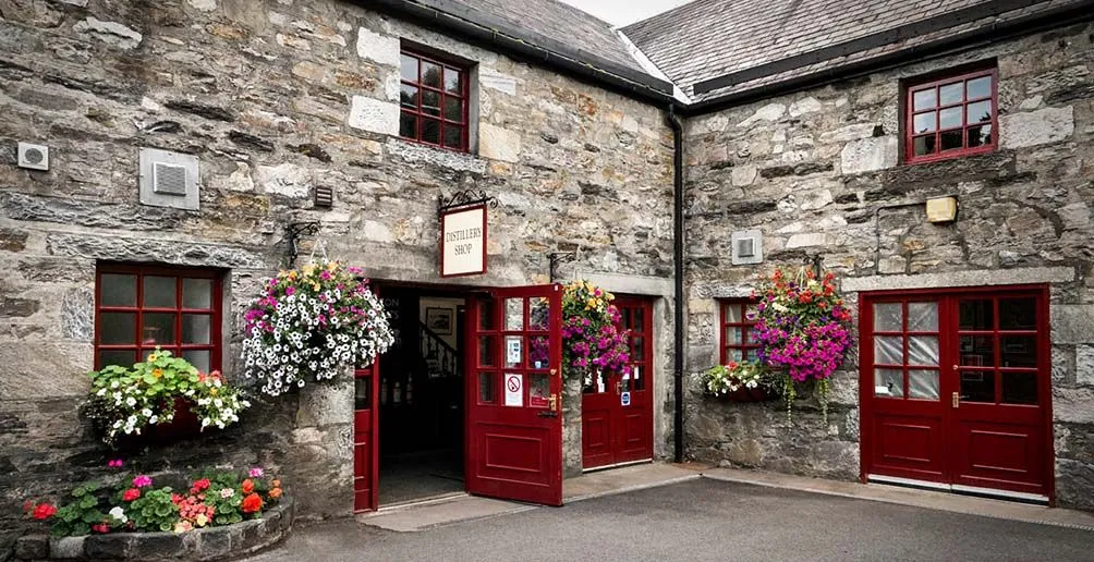Blair Athol's souvenir shop decorated with colorful flowers in full bloom hung on its stone walls next to the bright red doors