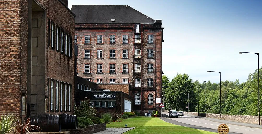 Deanston distillery building made out of red bricks with walls full of windows.