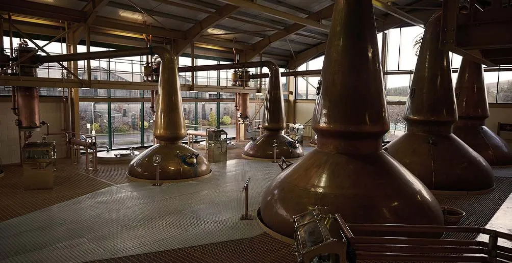 Five copper pot stills with lyne arms inside of Strathisla still house made of glass