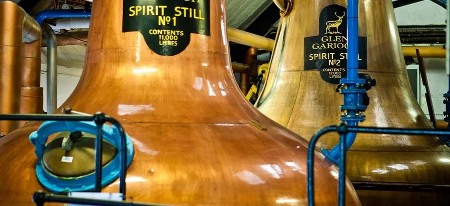 Close view on two numbered copper pot stills at Glen Garioch distillery with its name stickers attached on the upper body parts.