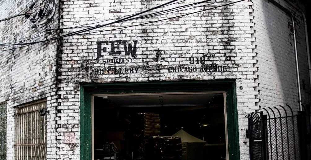 Entrance of FEW distillery building made out of brick with the brands' logo written above the green door