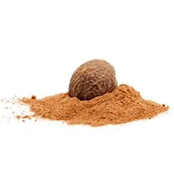 A pile of nutmeg powder with a whole nutmeg on top